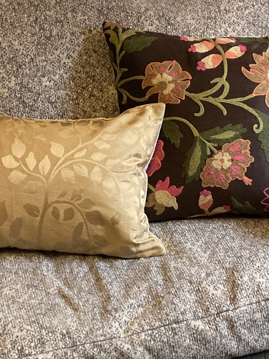 Two colorful pillows on a neutral sofa showing how different patterns can be used together in decorating