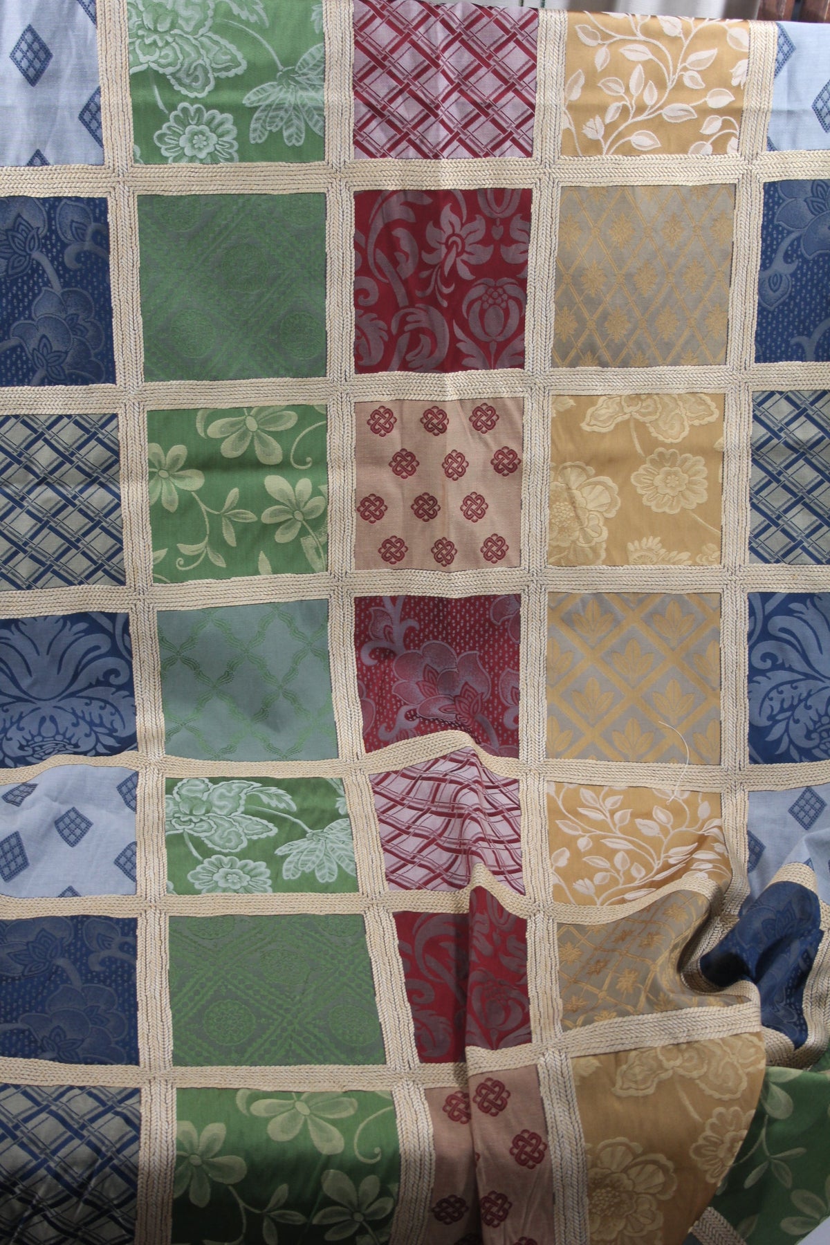 View of the fabric used to make the Multicolored Damask 18" pillow cover, which features repeating panels in red, blue, gold, and green, surrounded by gold thread borders.